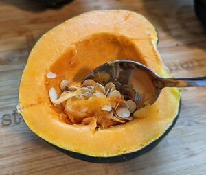 Acorn squash cut in half with a spoon scooping out the seeds