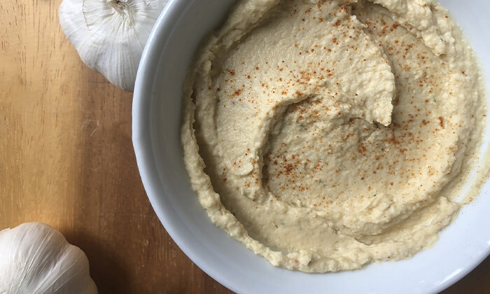 Fresh roasted cauliflower hummus in a white bowl with garlic