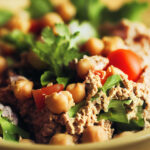 Vegan chickpea "tuna" salad in a bowl with greens, tomatoes, and whole chickpeas