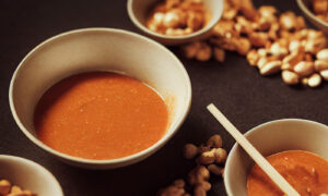 Peanut sauce next to peanuts in a bowl
