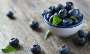 Fresh picked blueberries in a small bowl and on a table